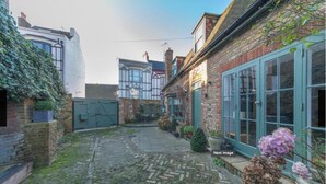 A courtyard with cobblestone paths, a brick building with large windows, and a green door. - Ramsgate - Coastal Cottage Escape - Pet Friendly with Parking (Ramsgate)