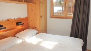 Una habitación de madera con una cama, una ventana y una cortina.