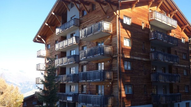 Un edificio de madera de varios pisos con balcones, probablemente un hotel o resort.