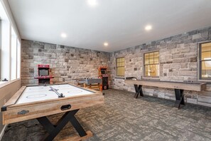 A room with a foosball table, two arcade machines, and a pool table.