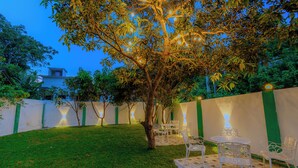 A well-maintained garden with a lawn, a tree, and outdoor seating area with chairs and a table. - Istana Villa Mirissa (Mirissa)