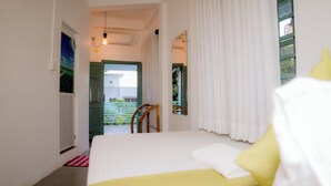 A bedroom with a bed, a chair, a window with curtains, and a door leading to a balcony. - Istana Villa Mirissa (Mirissa)