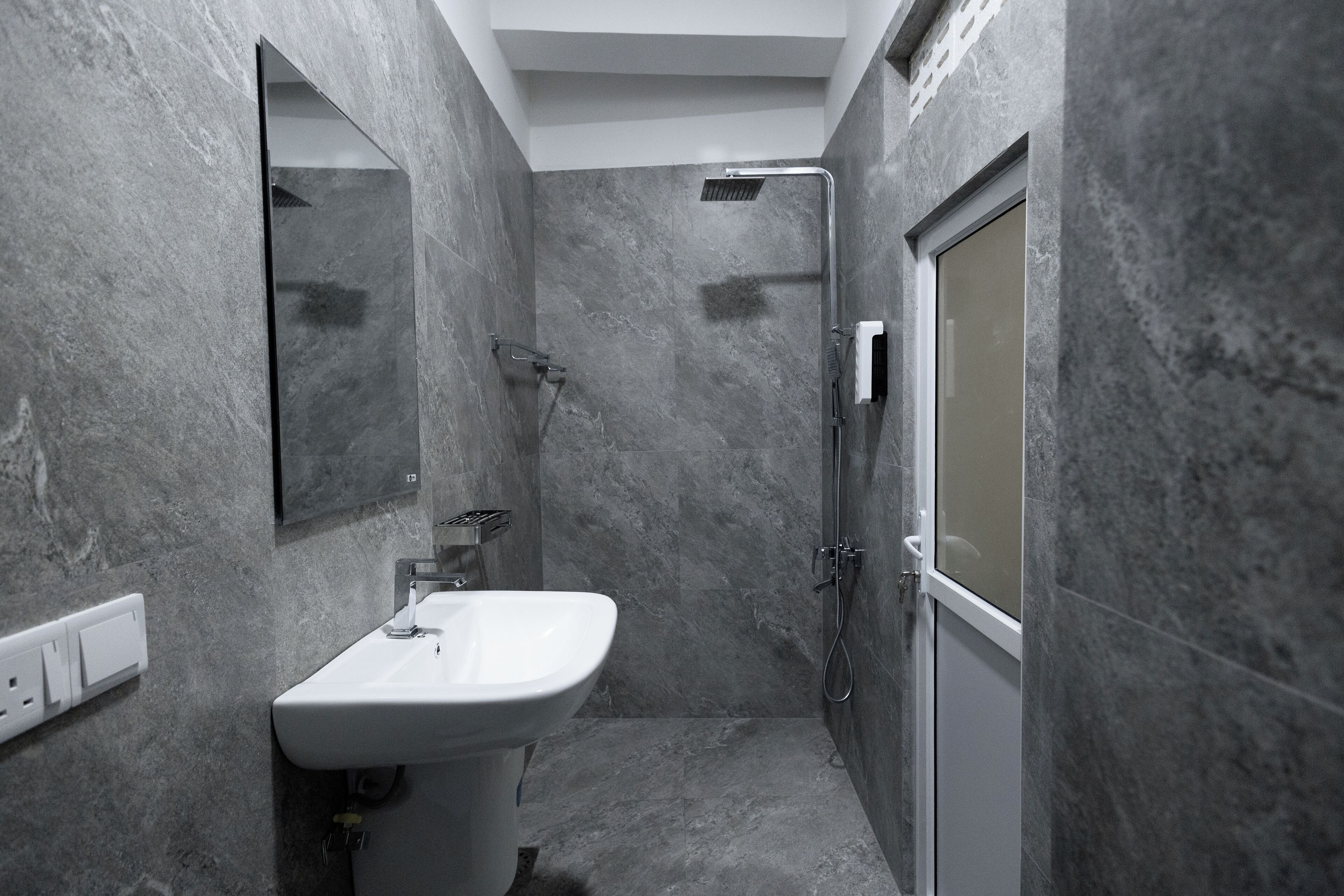 Une salle de bain moderne avec un lavabo blanc, une douche et un miroir.