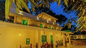 A well-lit building with a covered patio area, green shutters, and outdoor seating. - Istana Villa Mirissa (Mirissa)