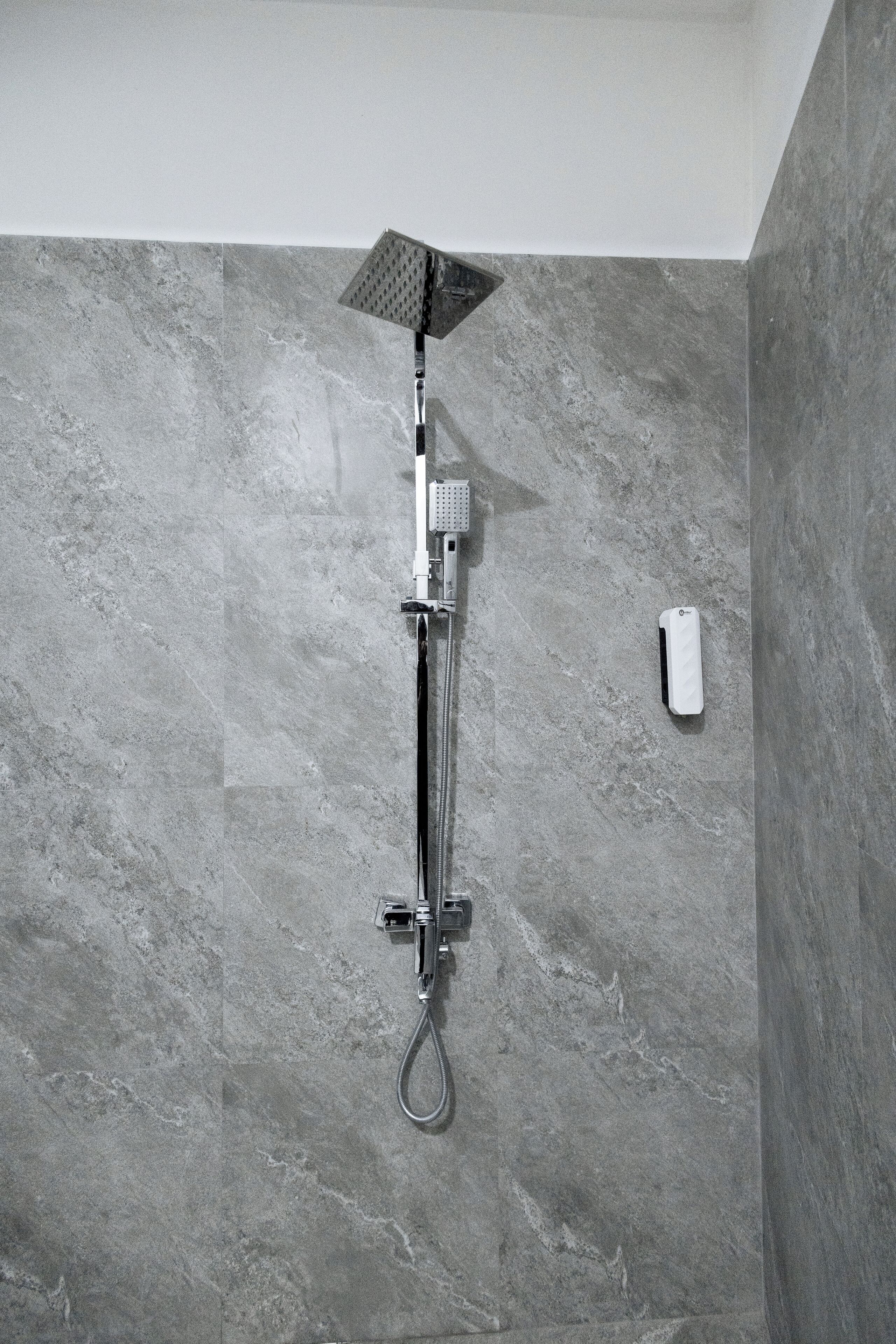 A modern shower with a handheld showerhead and a wall-mounted control panel.