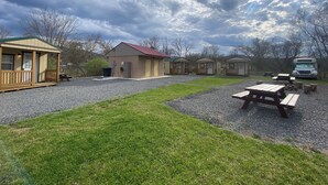 A campground with small cabins, picnic tables, and a gravel parking area. - Canal Cabins (Paw Paw)