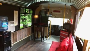 A compact interior with a kitchenette, a small dining area, and a red cushioned bench. - Canal Cabins (Paw Paw)