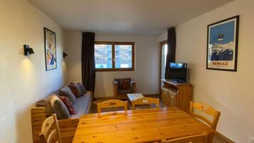 Una habitación acogedora con una mesa de madera, sillas, un sofá y un televisor.