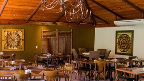 Ein Restaurant mit Holztischen und -stühlen, einer Kristallleuchter und Bildern an den Wänden.