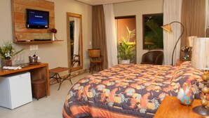 Ein Hotelzimmer mit einem großen Bett, einem Schreibtisch mit Computer, einem an der Wand befestigten Fernseher und einem kleinen Kühlschrank.