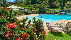 A pool area with lounge chairs and a covered seating area, surrounded by lush greenery and a hilly landscape. - Hotel Fazenda Parador Maritacas (Barra do Pirai)