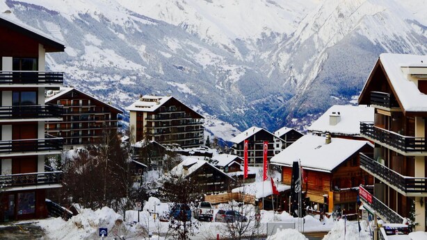 A mountain resort with chalet-style buildings, a ski lift, and snow-covered mountains in the background. - Apartment in the Heart of Valley (Nendaz)