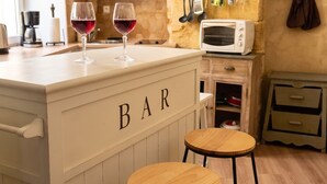 Une cuisine avec un coin bar, des tabourets en bois et un four à micro-ondes.