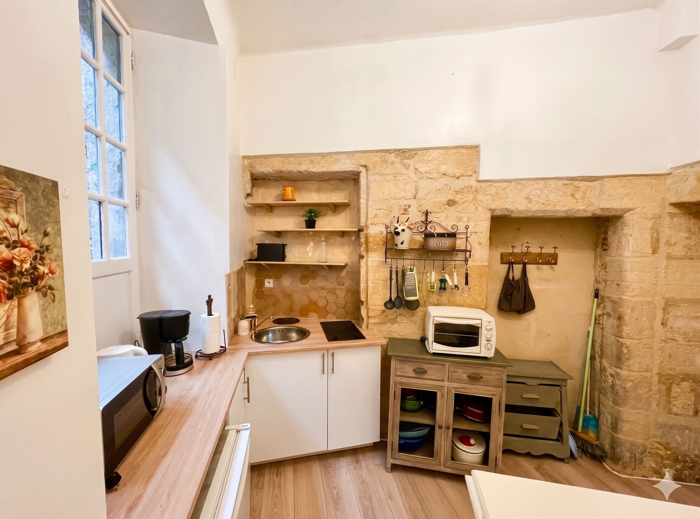 Een compacte keuken met een stenen muur, een magnetron, een spoelbak en een klein kastje met servies.