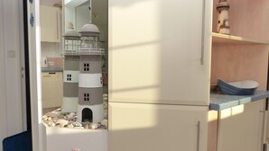 A compact kitchen with a built-in lighthouse model, a small sink, and a decorative bowl on the counter.