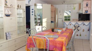 A dining area with a table set for two, a laptop, and a fish-themed wall decoration. - Les Courlis, holiday home near the beaches (Erdeven)