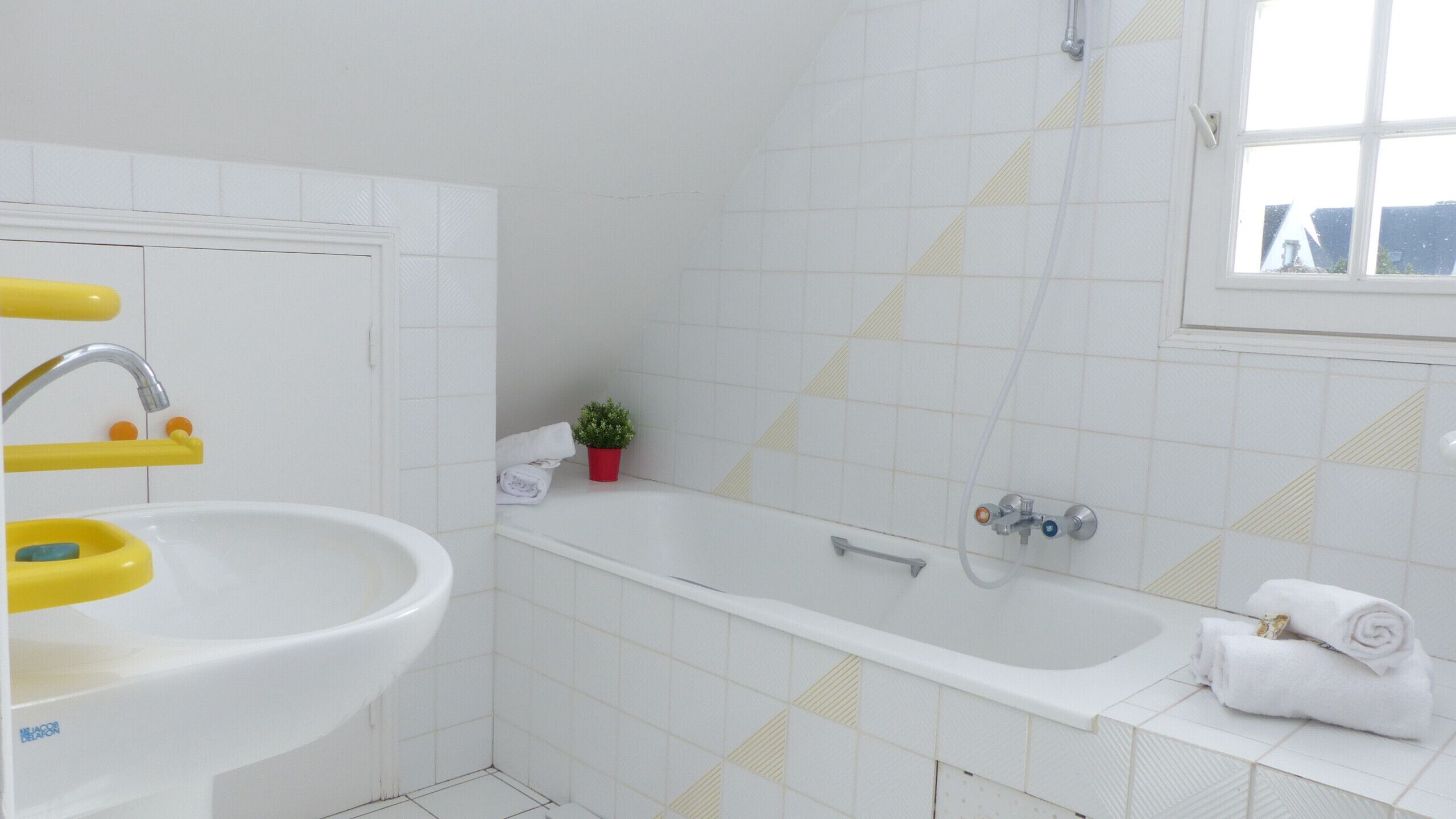 A bathroom with a white sink, a bathtub, and a window.
