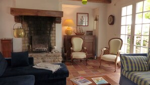 Un saló acollidor amb una llar de foc, dues butaques, un sofà i una taula amb revistes.