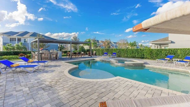 A swimming pool with lounge chairs, a covered seating area, and a view of surrounding buildings. - Gorgeous 5BR at Encore Resort next to Disney 7710 (Kissimmee)
