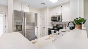 A modern kitchen with white cabinets, stainless steel appliances, and a marble countertop. - Charming 2-Bedroom Home...Pet Friendly...2 Min From Baptist East (Montgomery)