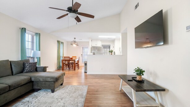 A modern living room with a sectional sofa, a coffee table, a dining area with a table and chairs, and a kitchen in the background. - Charming 2-Bedroom Home...Pet Friendly...2 Min From Baptist East (Montgomery)