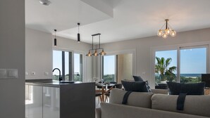 Une cuisine moderne dotée d’un îlot central, d’un coin repas offrant une vue dégagée et d’un espace salon confortable avec vue sur l’océan.
