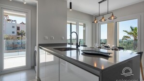 Une cuisine moderne dotée d’un grand îlot central, d’un évier intégré et de luminaires suspendus.