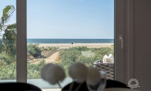 A view from a room with a window overlooking a beach, a wooden bridge, and some greenery. - Los Camaleones 4101 - Two Bedroom Apartment, Sleeps 5 (Punta del moral)