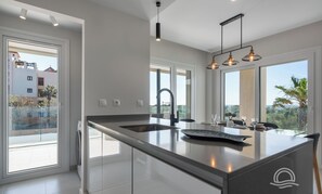 A modern kitchen with a large island, a built-in sink, and pendant lighting. - Los Camaleones 4101 - Two Bedroom Apartment, Sleeps 5 (Punta del moral)