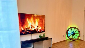 En moderne stue med et fladskærms-tv monteret på væggen, trægulv, blå sofa og en dekorativ cykel.