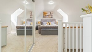 Quarto com duas camas, um espelho grande e um corrimão branco.