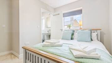 A bedroom with a bed, a window with a view, a bedside table, and a mirror.
