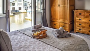 Une chambre d’hôtel avec un lit, une armoire en bois et une vue sur un canal bordé d’immeubles.