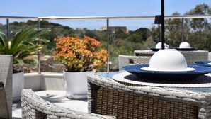 An outdoor dining area with wicker furniture, a table with a white plate and blue rim, and a potted plant with orange flowers. - 4-bedroom villa in enchanting Ix-Xagħra with WiFi, AC (Ix-Xagħra)
