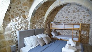 A bedroom with a stone wall, a bunk bed, a bedside table with a lamp, and neatly made beds. - 4-bedroom villa in enchanting Ix-Xagħra with WiFi, AC (Ix-Xagħra)