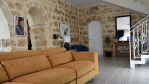 A living room with a stone wall, a sofa, a lamp, and a staircase. - 4-bedroom villa in enchanting Ix-Xagħra with WiFi, AC (Ix-Xagħra)