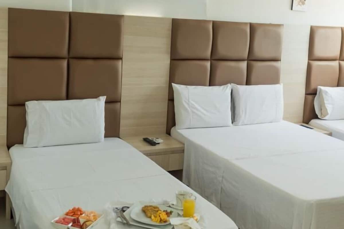 Une chambre d’hôtel avec deux lits, une petite table avec le petit-déjeuner et un luminaire au plafond.