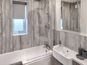 A modern bathroom with a bathtub, a shower, a sink, and a window. - 1 bedroom accommodation in Filey (Filey)