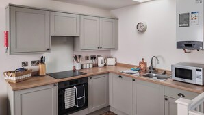 A modern kitchen with grey cabinets, a microwave, a sink, and a toaster.