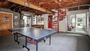 A ping pong table in a room with a wooden ceiling, a red spiral staircase, and a door leading to a balcony. - Charming 4-bedroom house with AC and WiFi in delightful Troutman (Troutman)