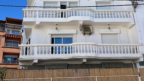 A multi-story building with balconies, air conditioning units, and a decorative fence. - Paddle Out Morocco (Tamraght)