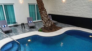 An indoor swimming pool with a tiled edge, lounge chairs, and a palm tree. - FCH Hotel Minerva-CAS (Guadalajara)