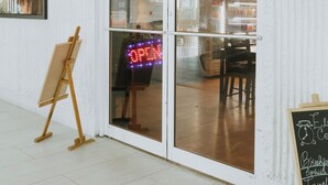 Un café dont l’enseigne porte l’inscription « Elites Coffee Shop » et qui est agrémenté d’un néon clignotant indiquant « OUVERT ».