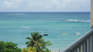 Une vue sur l’océan, avec plusieurs bateaux, une plage et des palmiers.