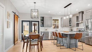 A modern kitchen with a central island, bar stools, and stainless steel appliances. - NEW Dream Weaver - 5 min Walk to Main Street! (Weaverville)