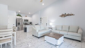 A spacious living area with a white sofa, a wooden coffee table, and a dining set. - Poolside | Lake Views | Game Room | 2-Min to SDC (Branson)