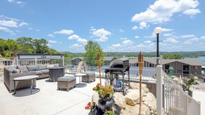 Una terraza en la azotea con mobiliario exterior, una parrilla y vistas al lago.