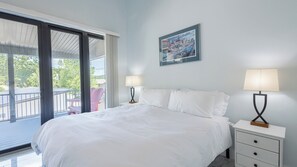Un dormitorio con una cama, dos mesitas de noche con lámparas, una ventana y un cuadro en la pared.