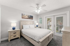 A bedroom with a bed, nightstands, a ceiling fan, and a view through a door. - Palm Breeze Retreat Sleeps 10! (Panama City Beach)