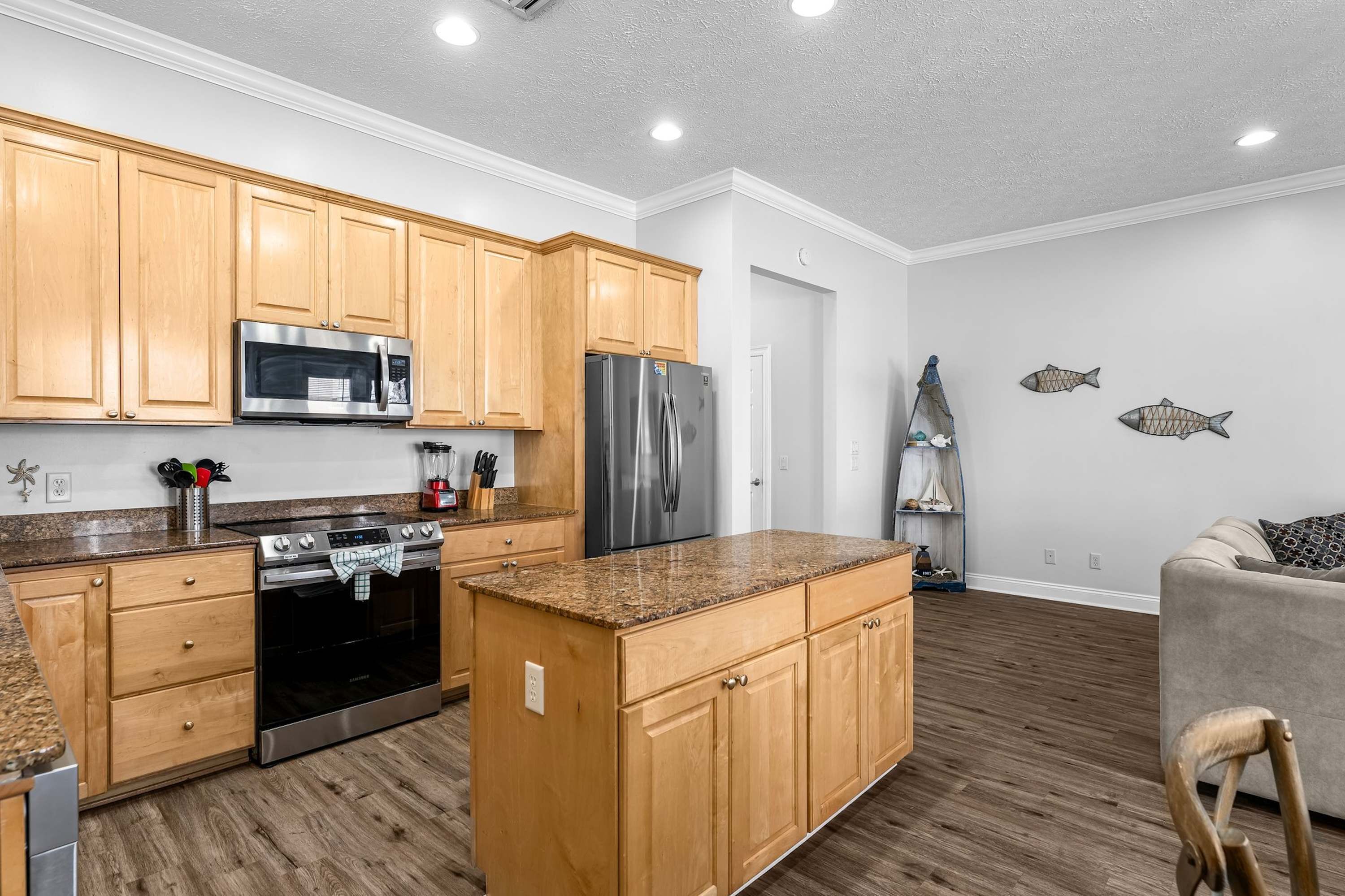 A modern kitchen with wooden cabinets, stainless steel appliances, and a granite countertop.